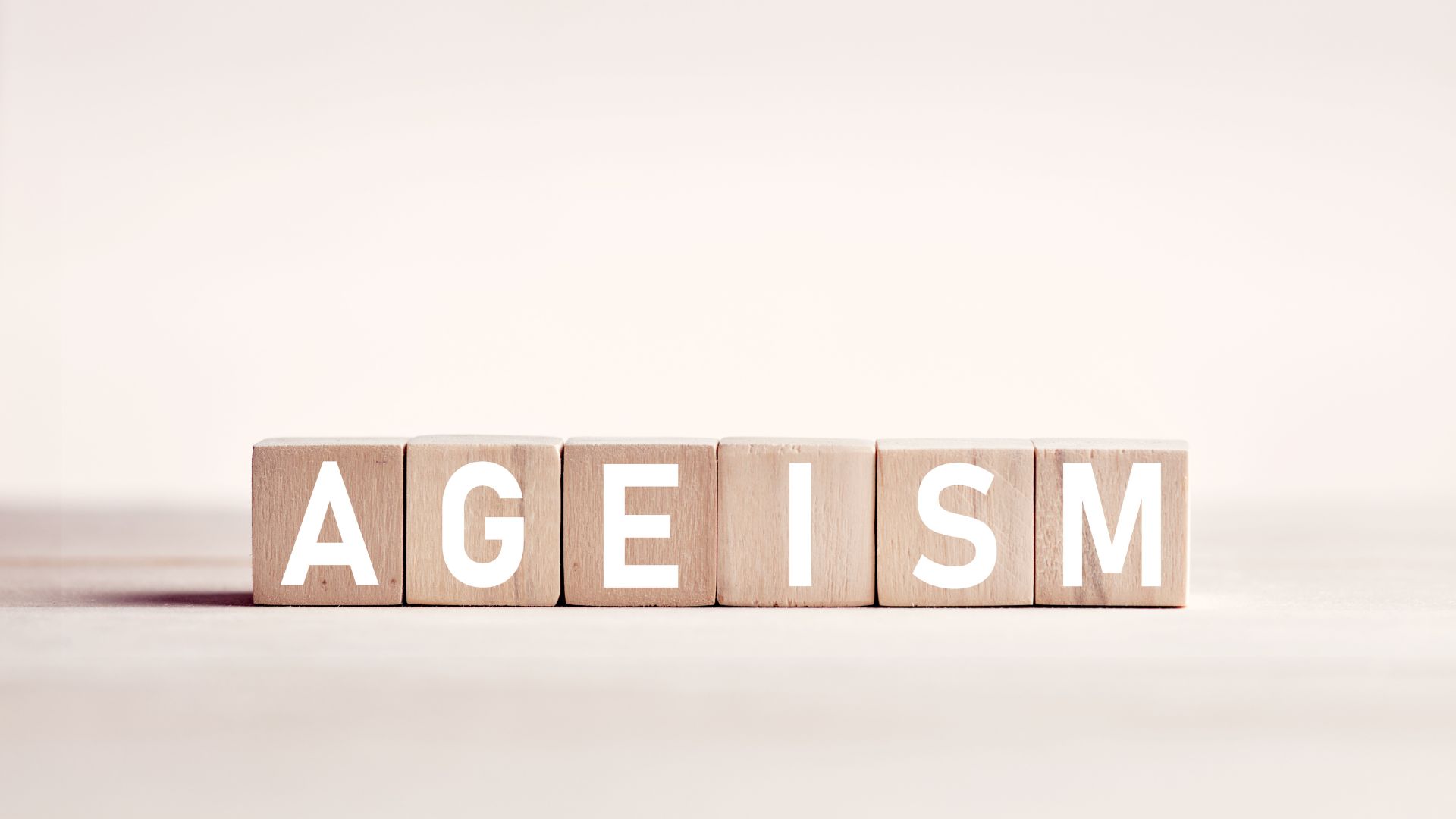 The word ageism on wooden blocks against white background.